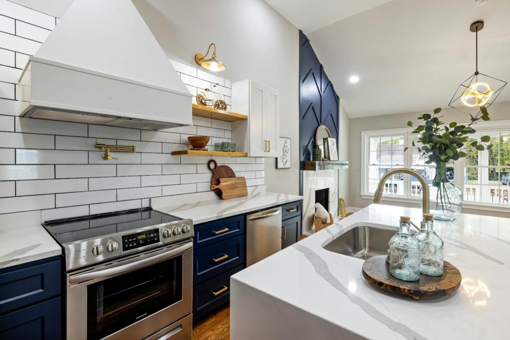 A modern kitchen featuring marble countertops, a stainless steel stove, and elegant blue cabinets.