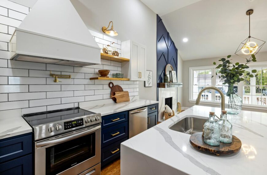 A modern kitchen featuring marble countertops, a stainless steel stove, and elegant blue cabinets.