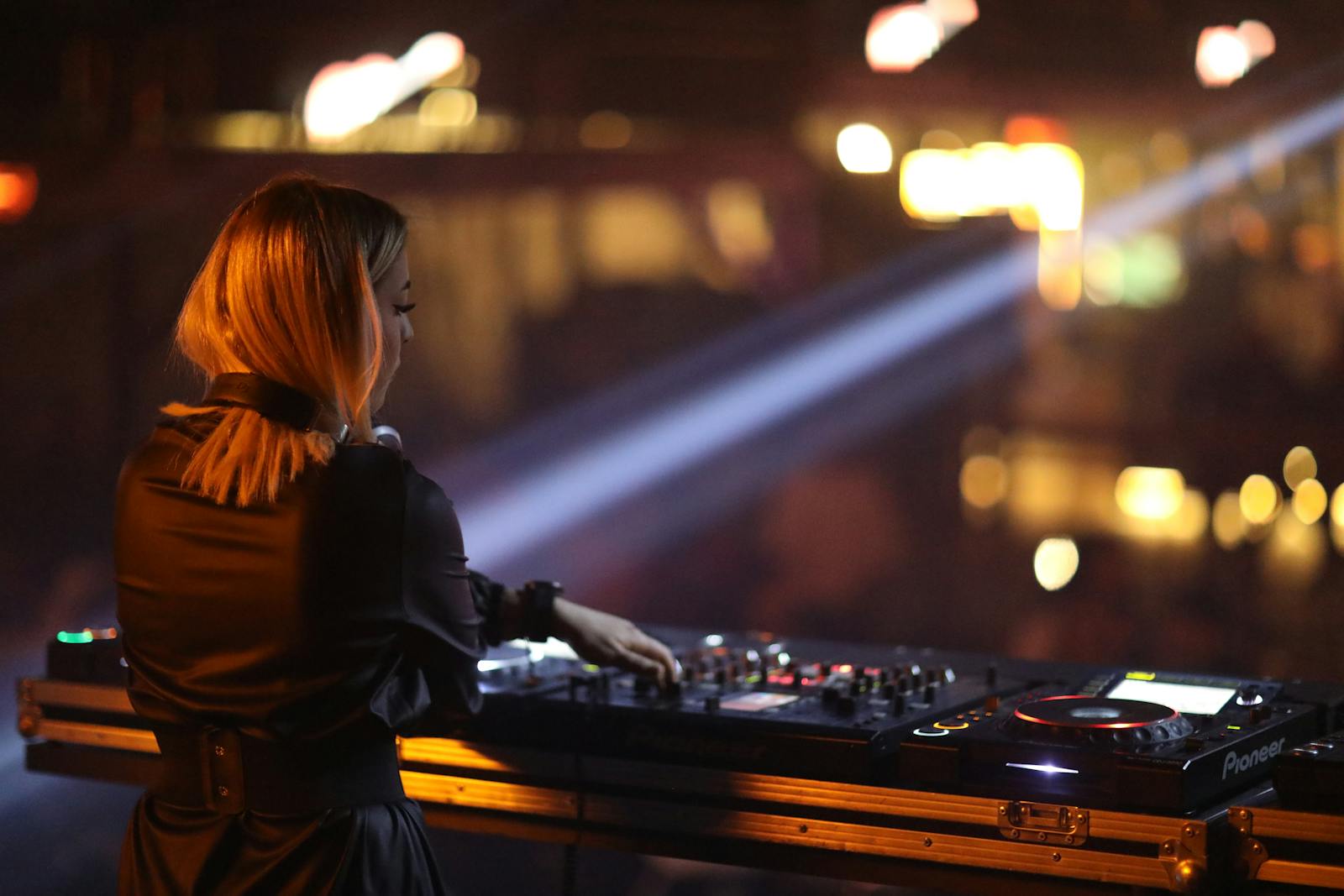 A young female DJ skillfully mixing tracks in a lively nightclub scene, showcasing music and nightlife vibes.