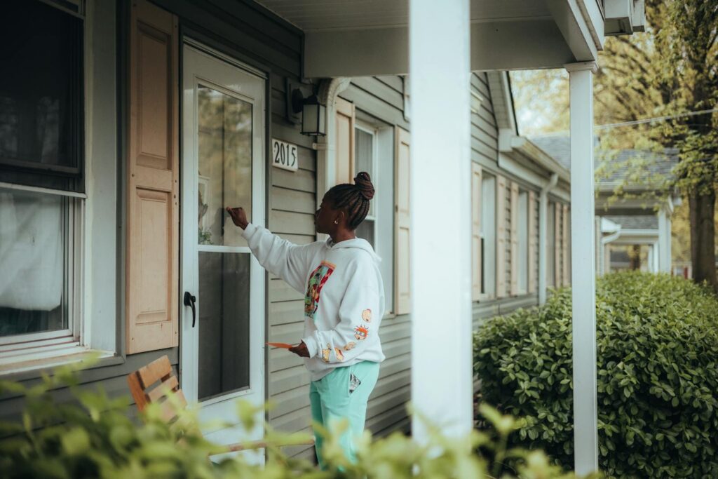 Young woman knocking on a front door in a suburban neighborhood.