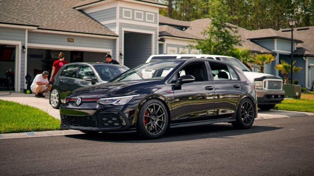 A modern suburban neighborhood featuring a stylish car parked on a driveway.