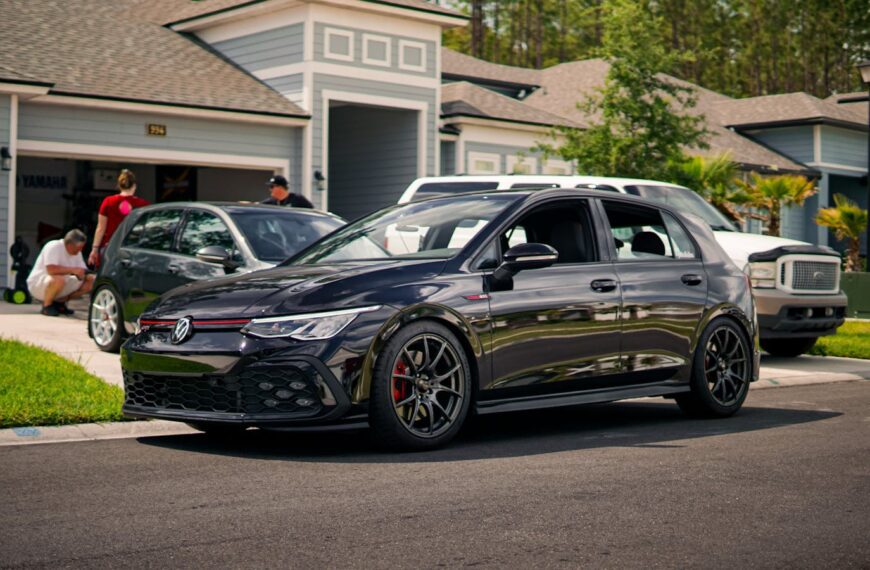A modern suburban neighborhood featuring a stylish car parked on a driveway.