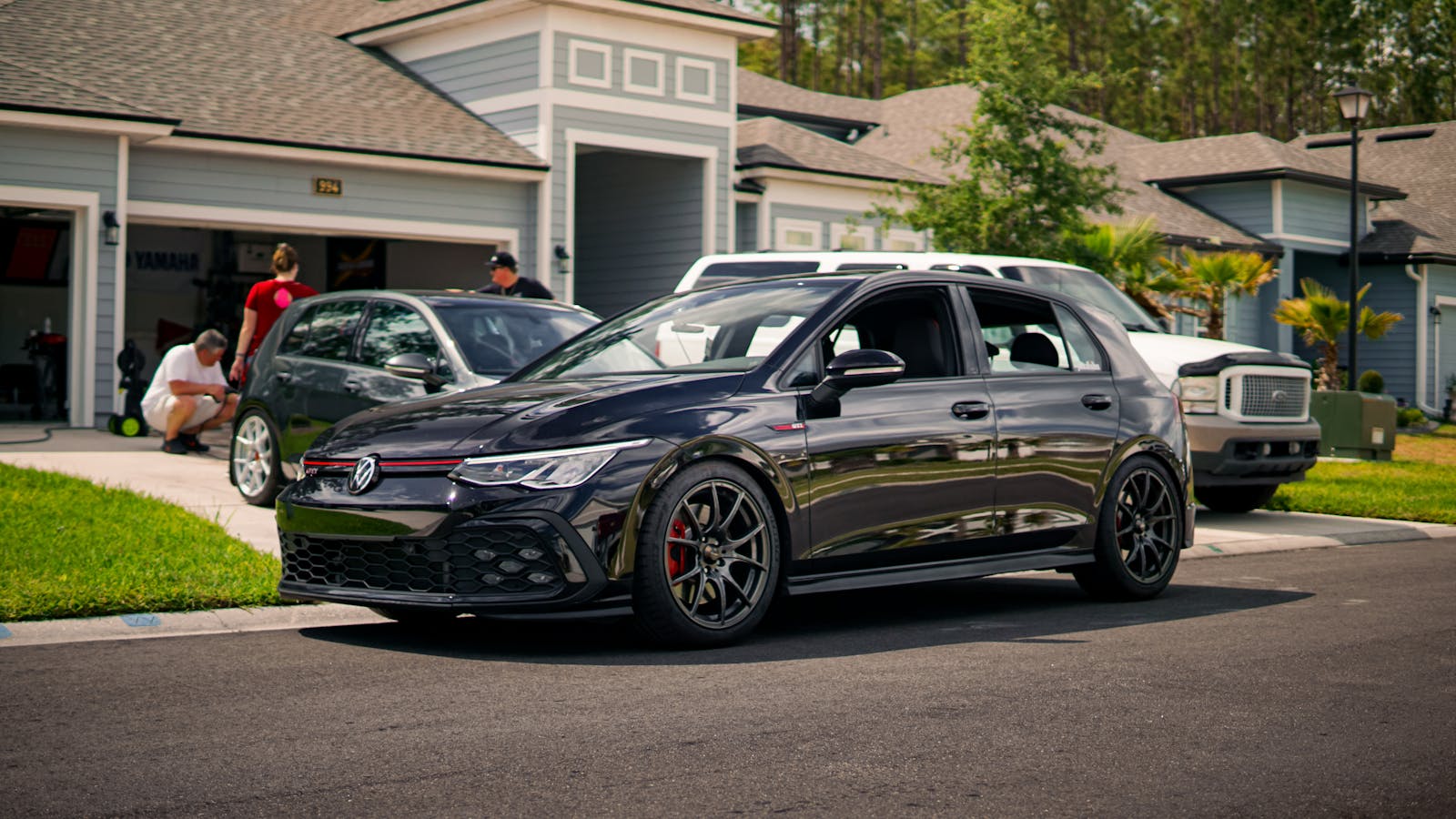 A modern suburban neighborhood featuring a stylish car parked on a driveway.