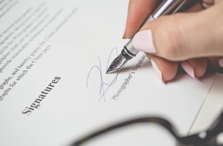 Close-up of a hand signing a contract, showcasing a pen and elegant handwriting.