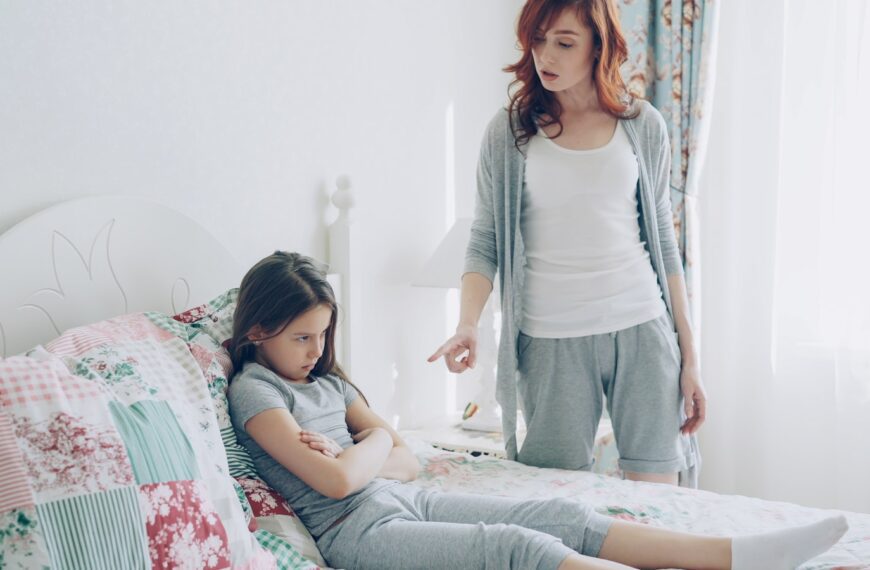 Mother scolds her daughter, who is sitting on the bed.