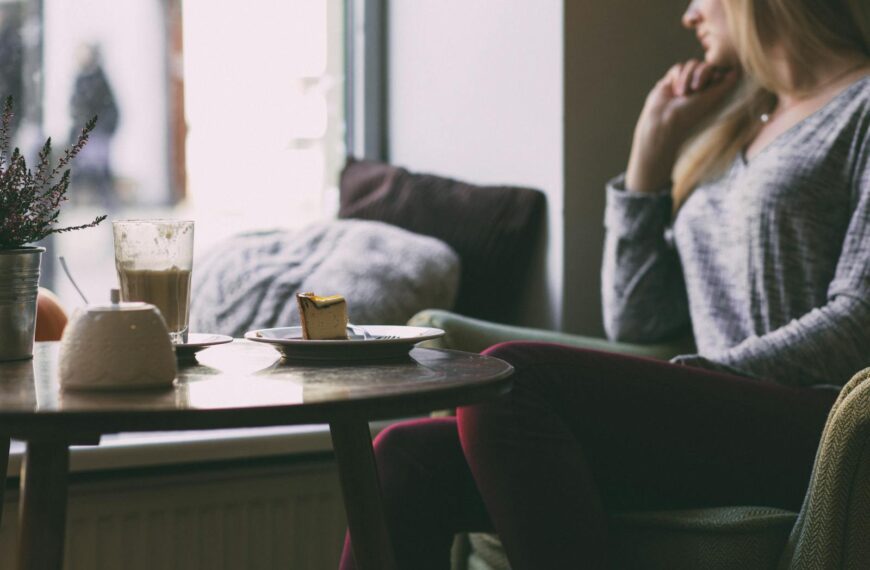 A woman enjoys a quiet moment in a cafe with a slice of cake and coffee.
