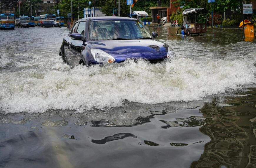 A blue car drives through flooded streets in Kolkata, India after heavy rain.