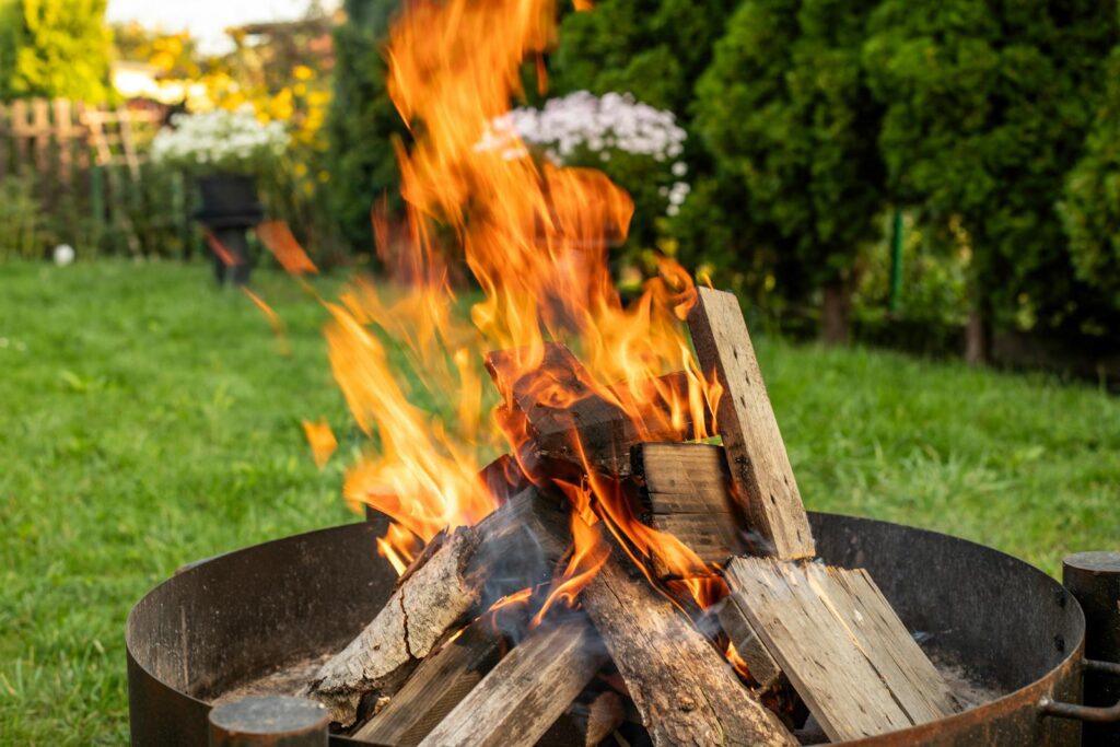 Vibrant bonfire with flaming logs, creating warmth and ambiance in a garden setting.