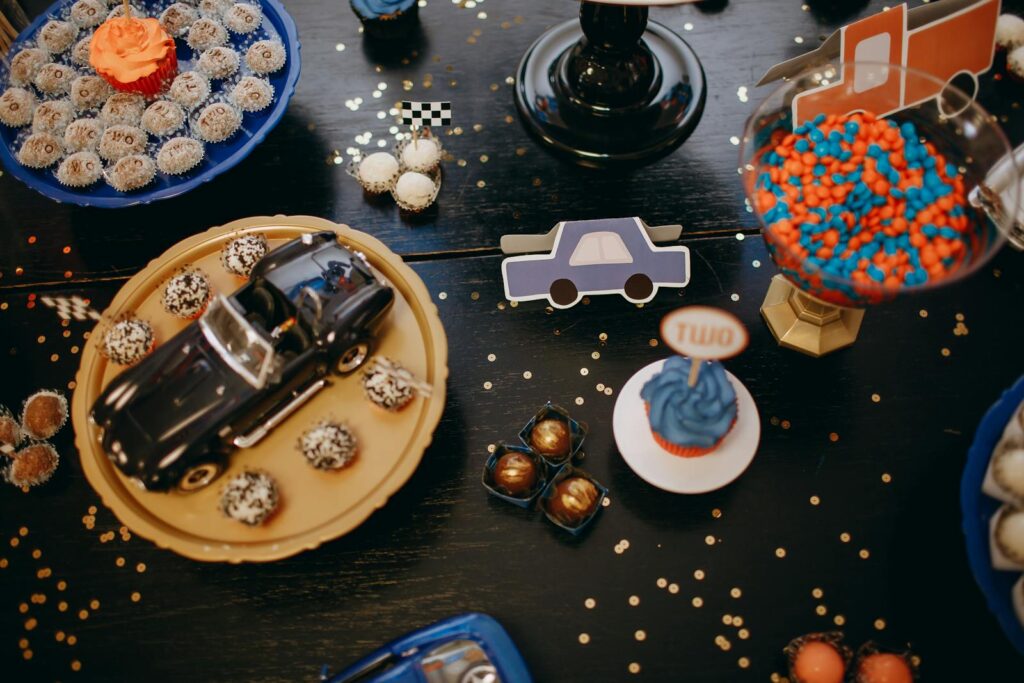 Vibrant birthday table setup with cupcakes, toy car, and candy for a festive celebration.