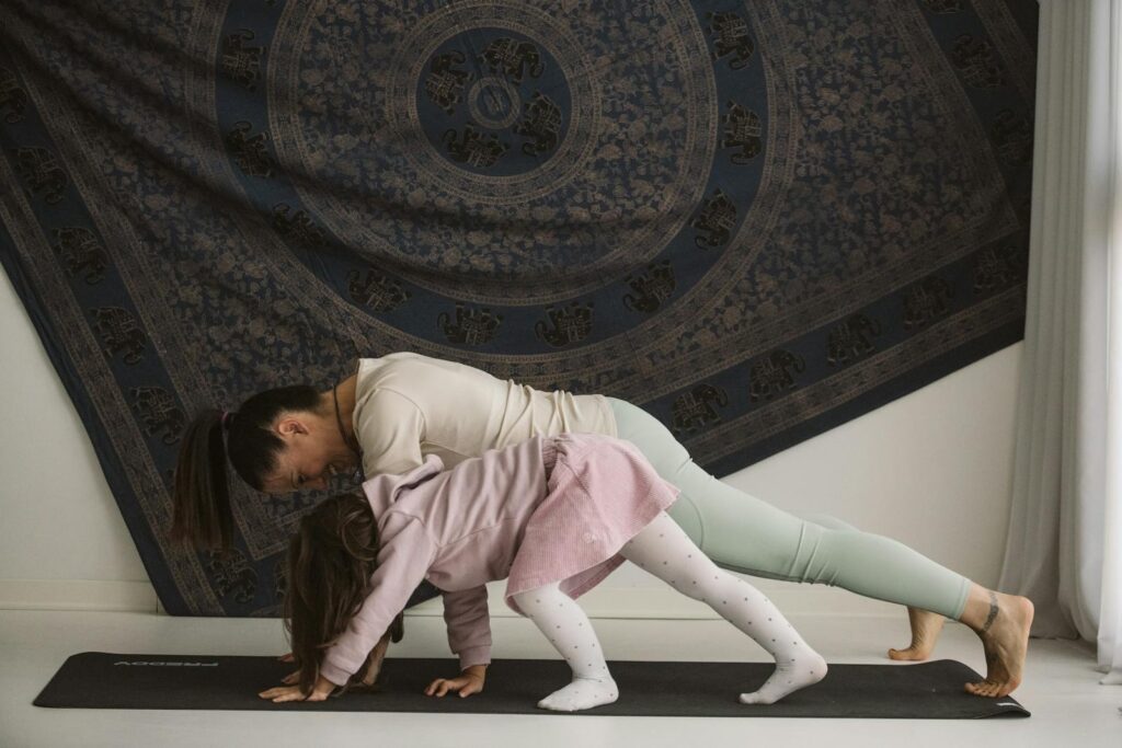 A mother and child practicing yoga together indoors, showcasing family bonding and wellness.