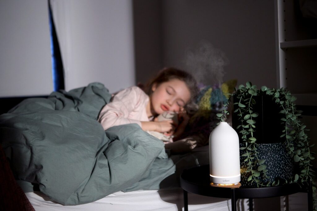 a woman laying in bed with a humidifier next to her