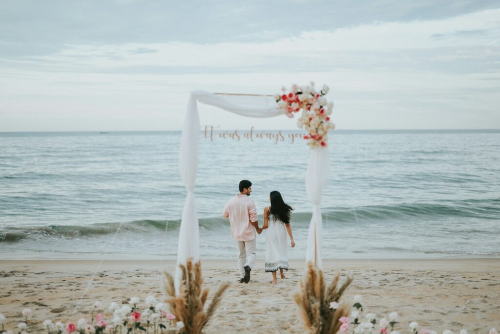 Couple holding hands at beach wedding ceremony