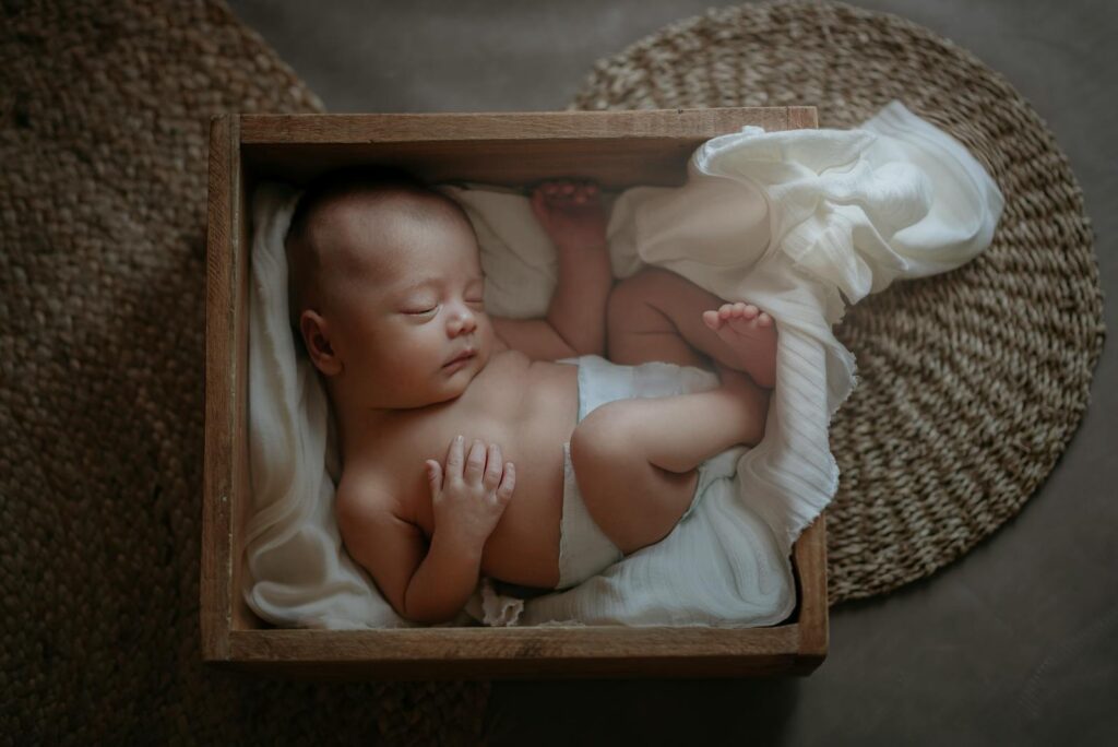 A serene sleeping baby resting in a wooden box with soft fabric, creating a warm and cozy ambiance.