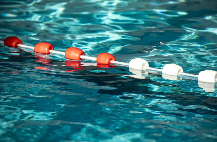Colorful pool buoys creating striking contrast on rippled blue water surface.