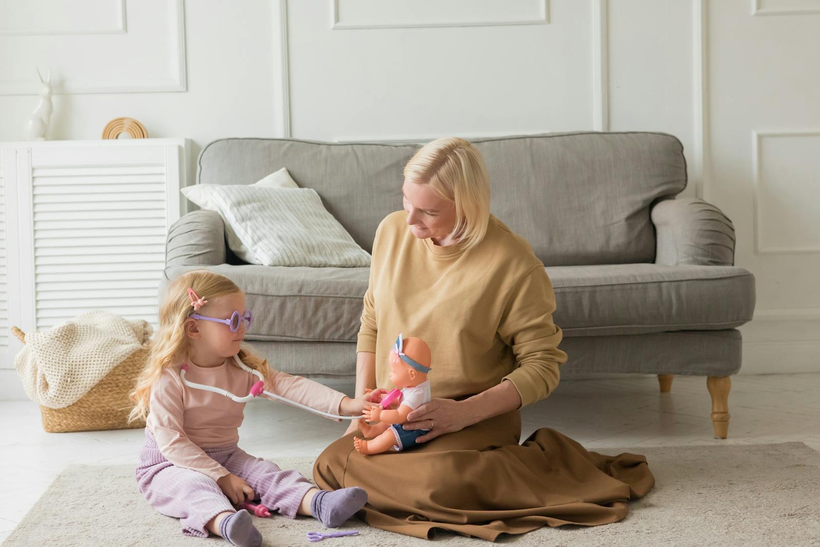 A mother and daughter enjoy quality time together, playing with a toy doll indoors.