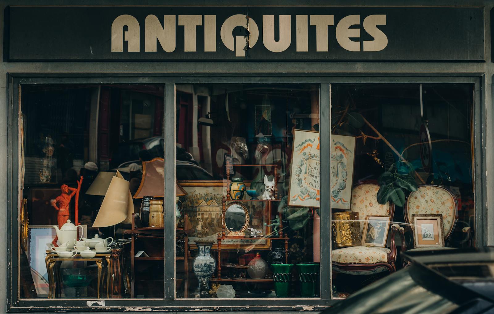 Explore a quaint Parisian antique shop with an elegant window display showcasing vintage treasures.