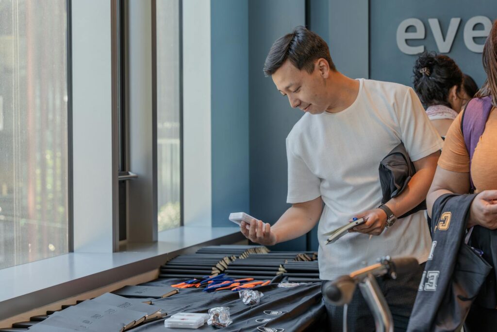 Adult man examines items at a table indoors during a community event, showcasing engagement.