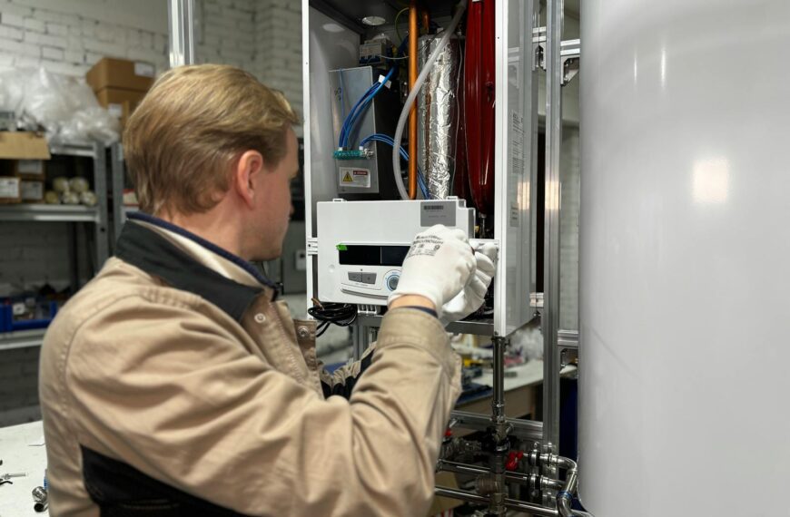 Technician installing or repairing a heating system in an indoor workshop setting.