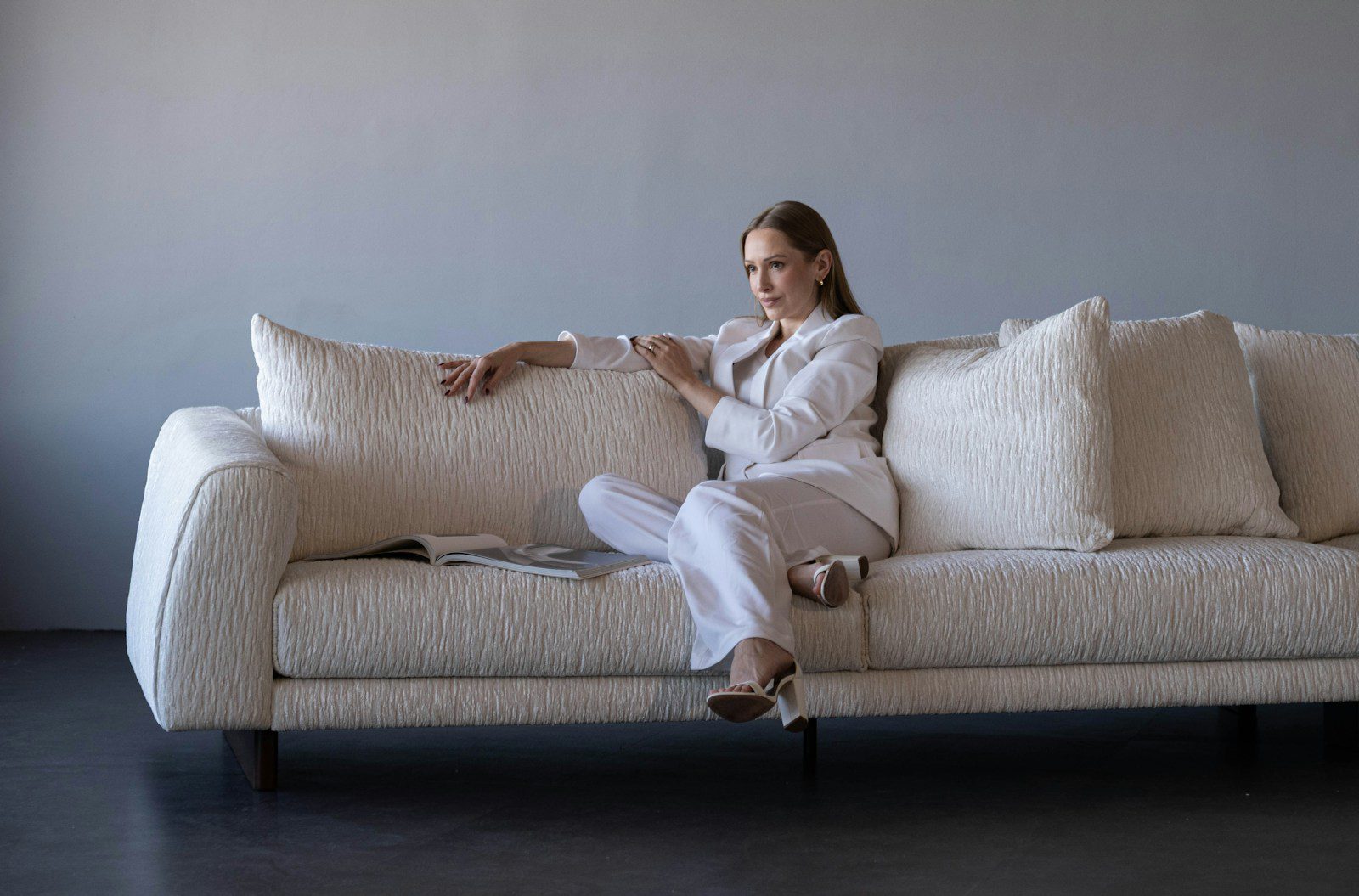 Woman in white suit sitting on a textured sofa.