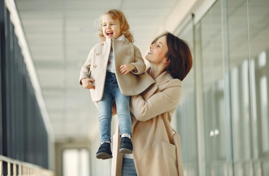 A cheerful mother lifts her joyful young daughter. Capturing a moment of happiness and bonding indoors.