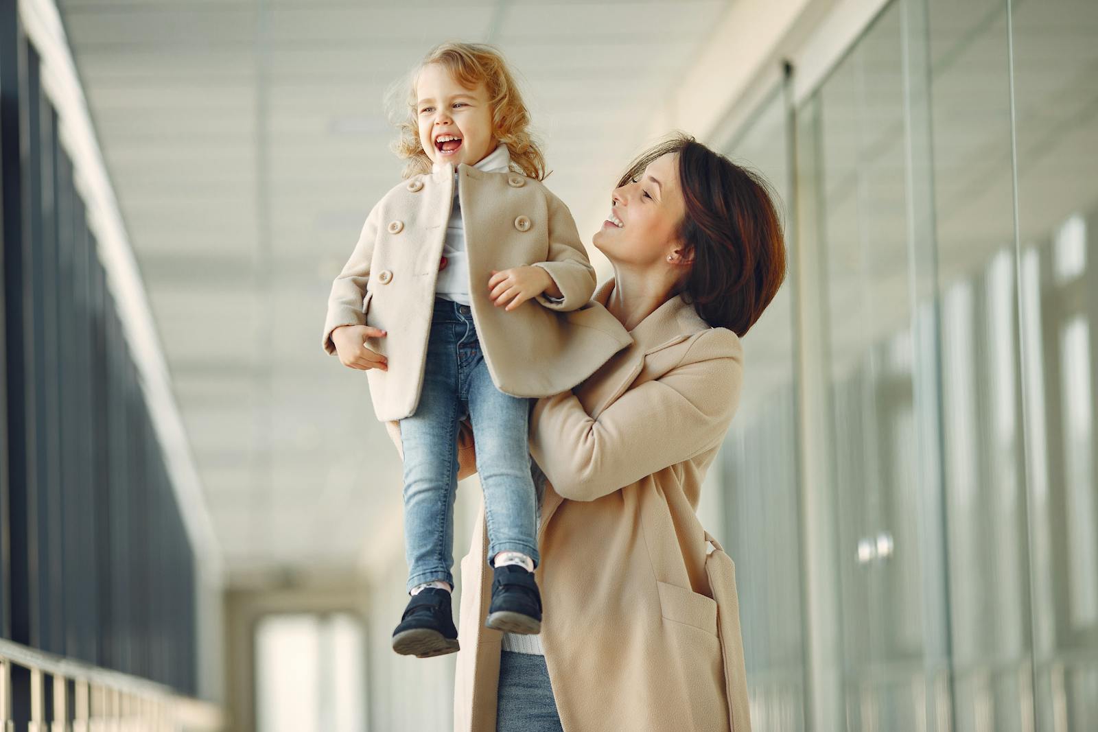 A cheerful mother lifts her joyful young daughter. Capturing a moment of happiness and bonding indoors.