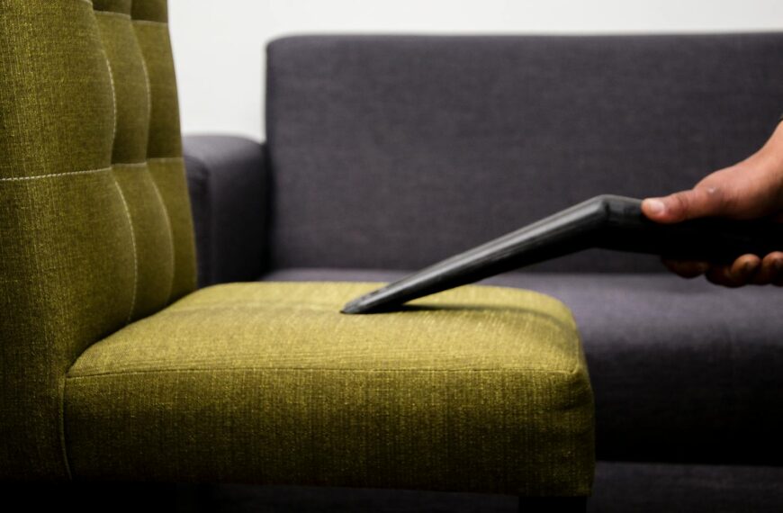 Close-up of a person vacuuming a modern sofa chair indoors, highlighting cleaning service.