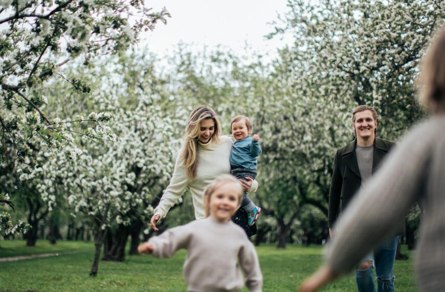 A joyful family enjoys a playful day outdoors amidst blossoming trees in spring.