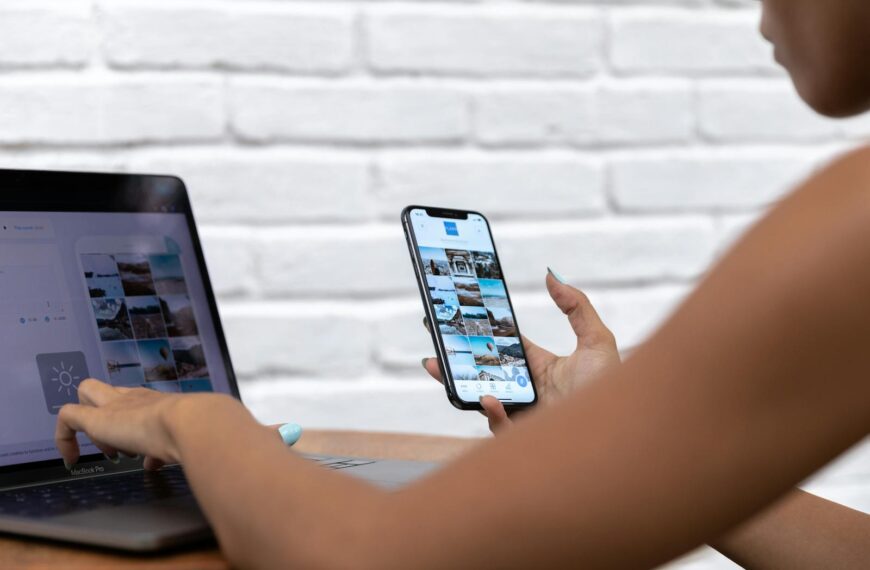 A woman working remotely using a laptop and smartphone, focusing on social media content.
