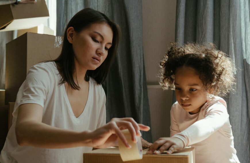 A young mother and her daughter packing moving boxes in their new home.