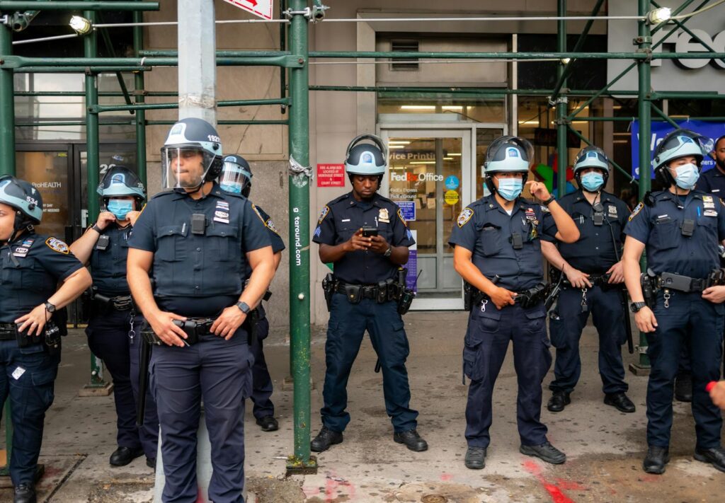 Police officers in full uniform and helmets stand in urban setting, ensuring public safety.