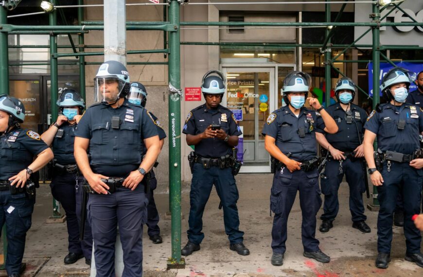 Police officers in full uniform and helmets stand in urban setting, ensuring public safety.