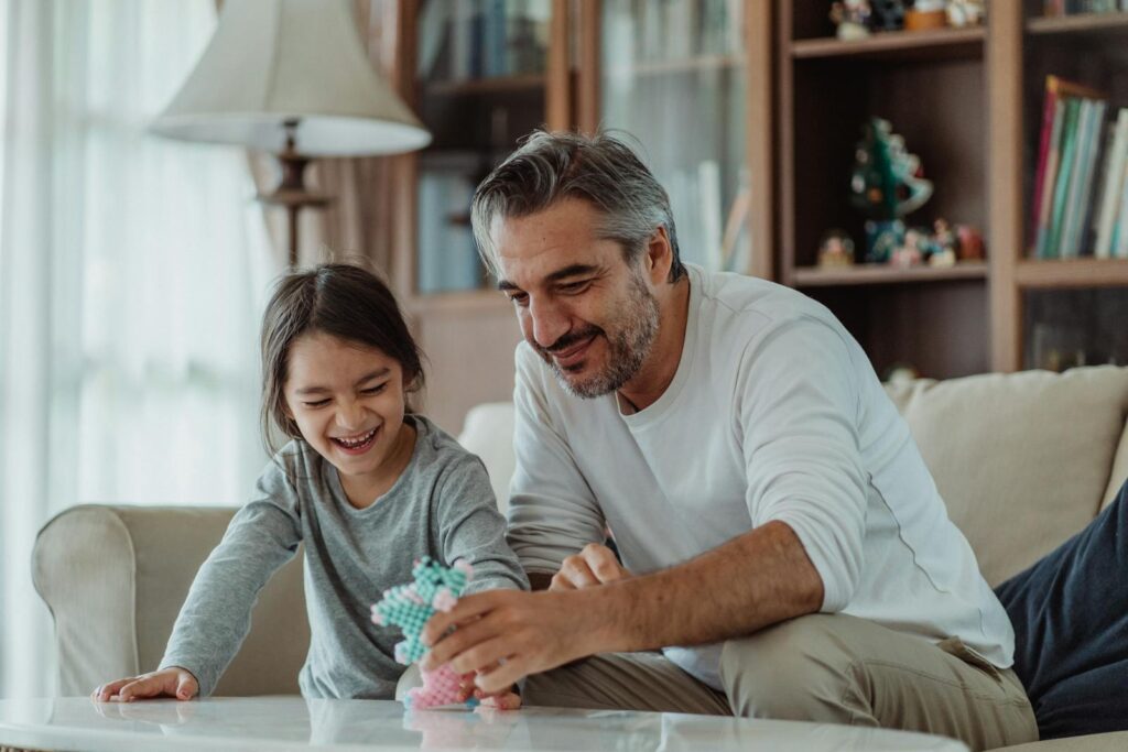 Father and daughter bonding and playing together on a sofa, creating joyful family moments.