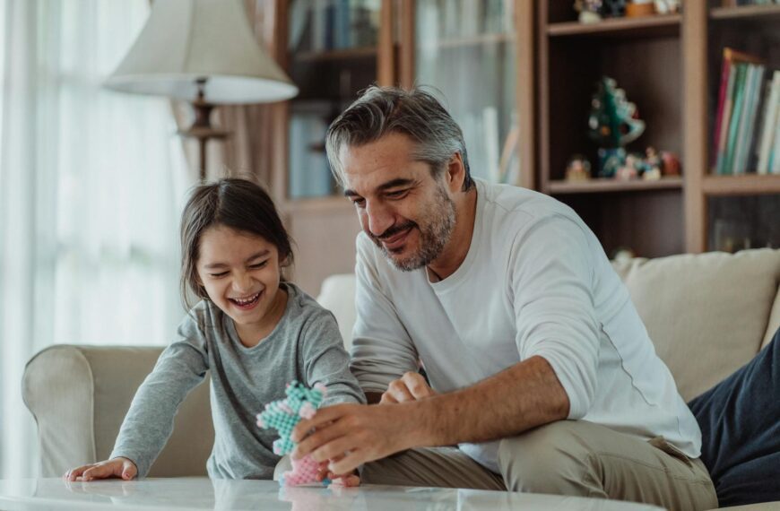 Father and daughter bonding and playing together on a sofa, creating joyful family moments.