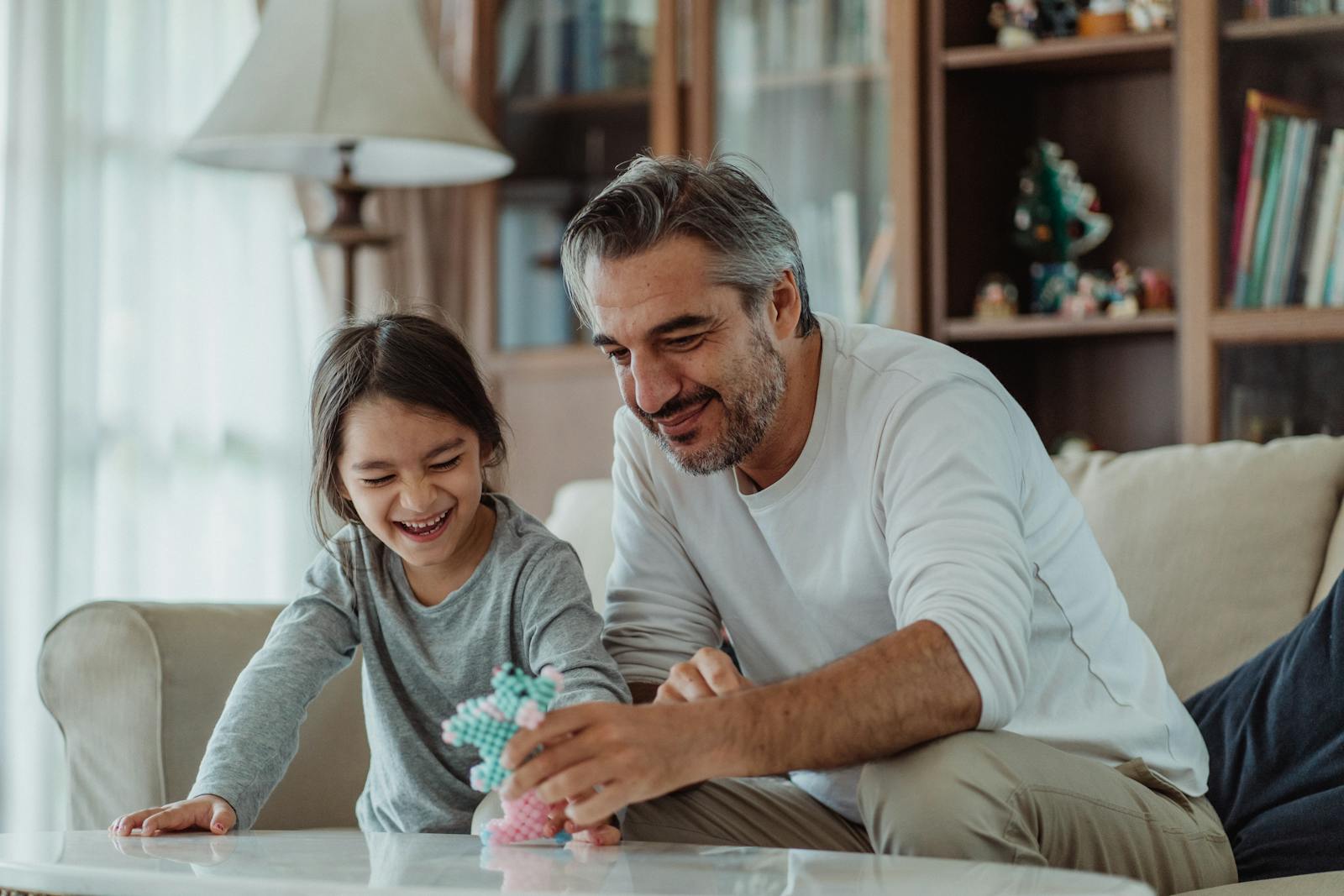 Father and daughter bonding and playing together on a sofa, creating joyful family moments.