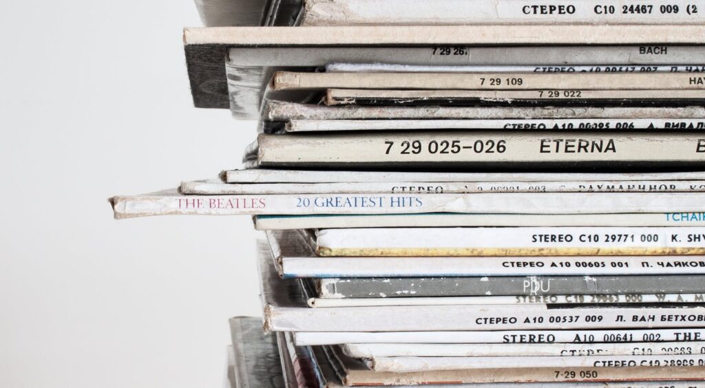Close-up shot of a stacked pile of vintage vinyl record albums showcasing classic music covers.