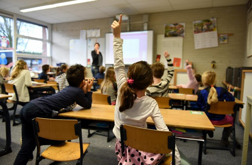 Lively classroom scene with students participating actively, raising hands for a lesson.