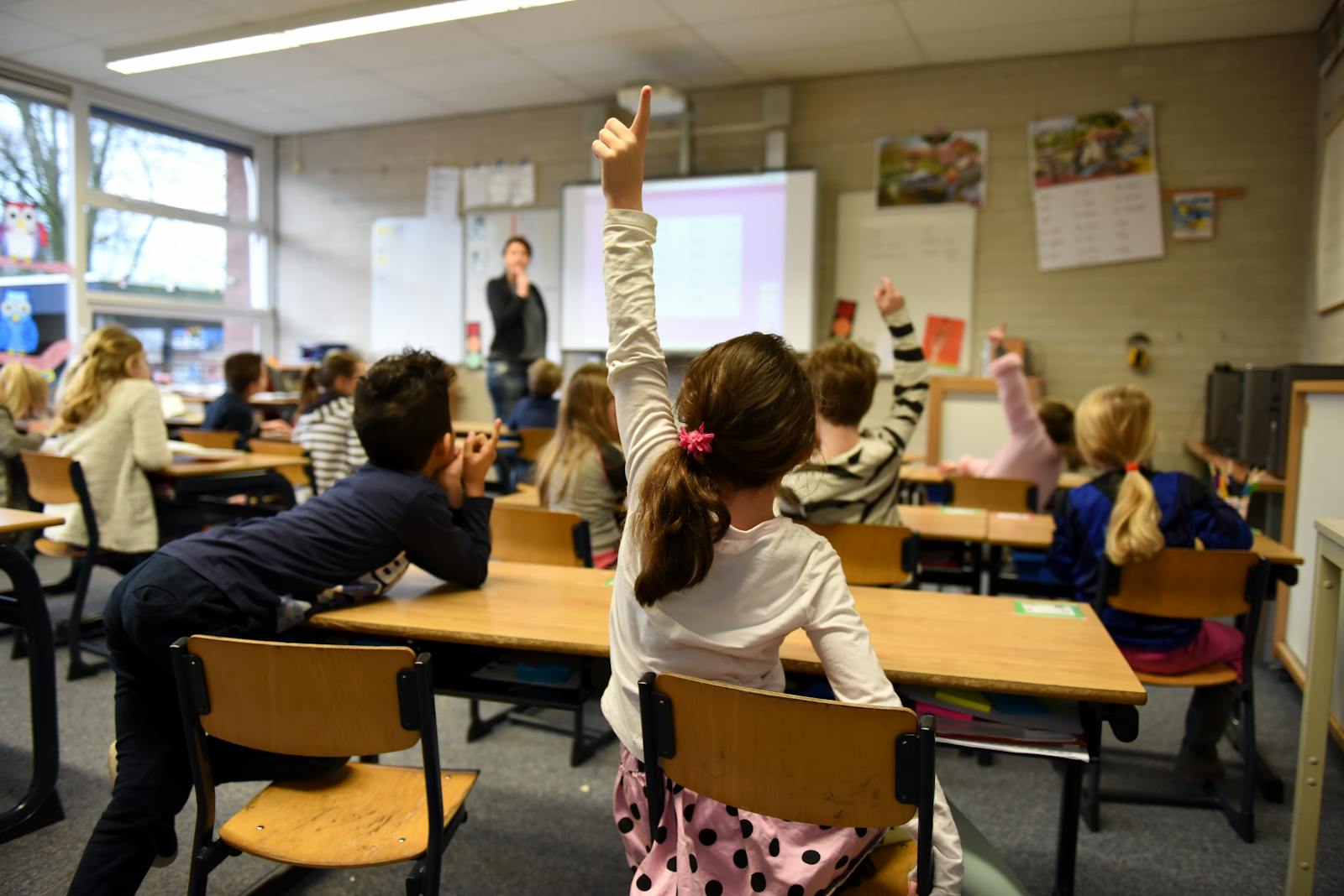 Lively classroom scene with students participating actively, raising hands for a lesson.
