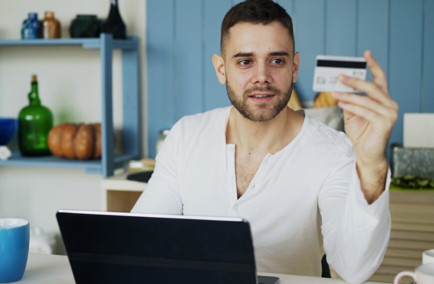 Man holding credit card while looking at laptop