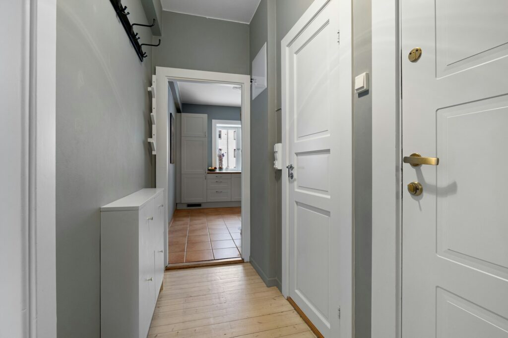 A long hallway with two white doors and a hard wood floor