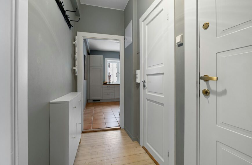 A long hallway with two white doors and a hard wood floor