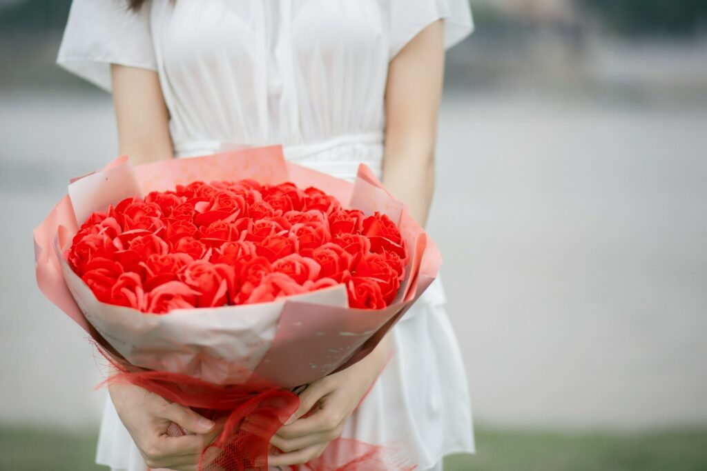 a woman holding a bouquet of red roses