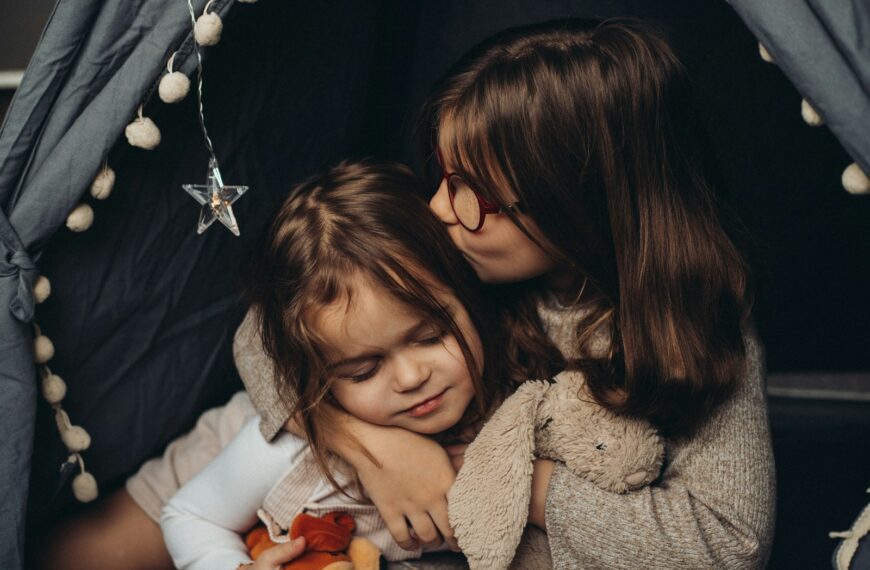 two little girls hugging each other in a tent