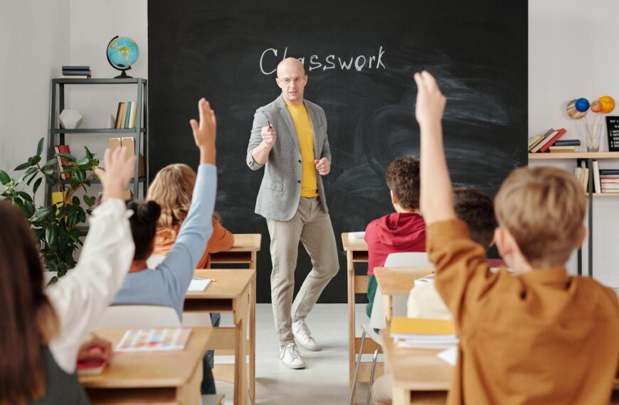 Teacher interacting with students raising hands in a classroom setting.