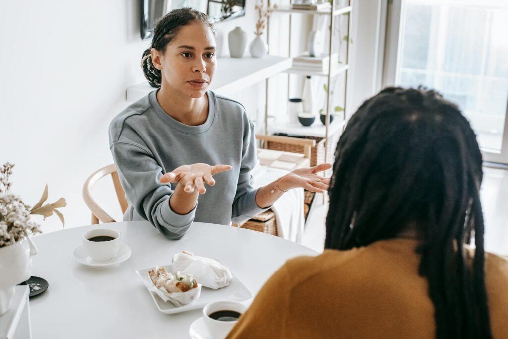 Young African American woman sitting at table and arguing with man in casual outfit in daylight