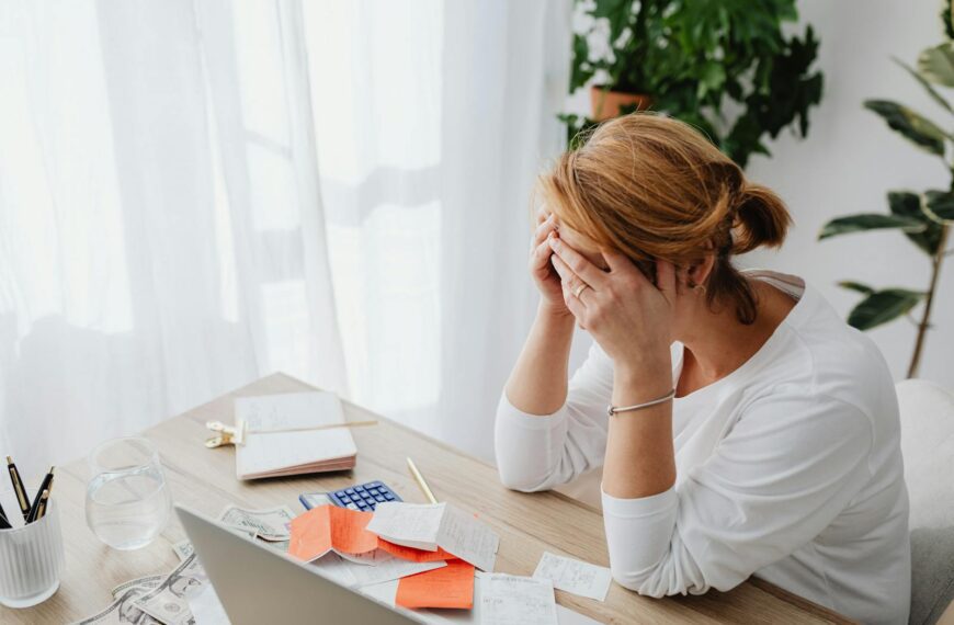 Woman stressed over financial receipts at a desk, dealing with expenses and calculations.
