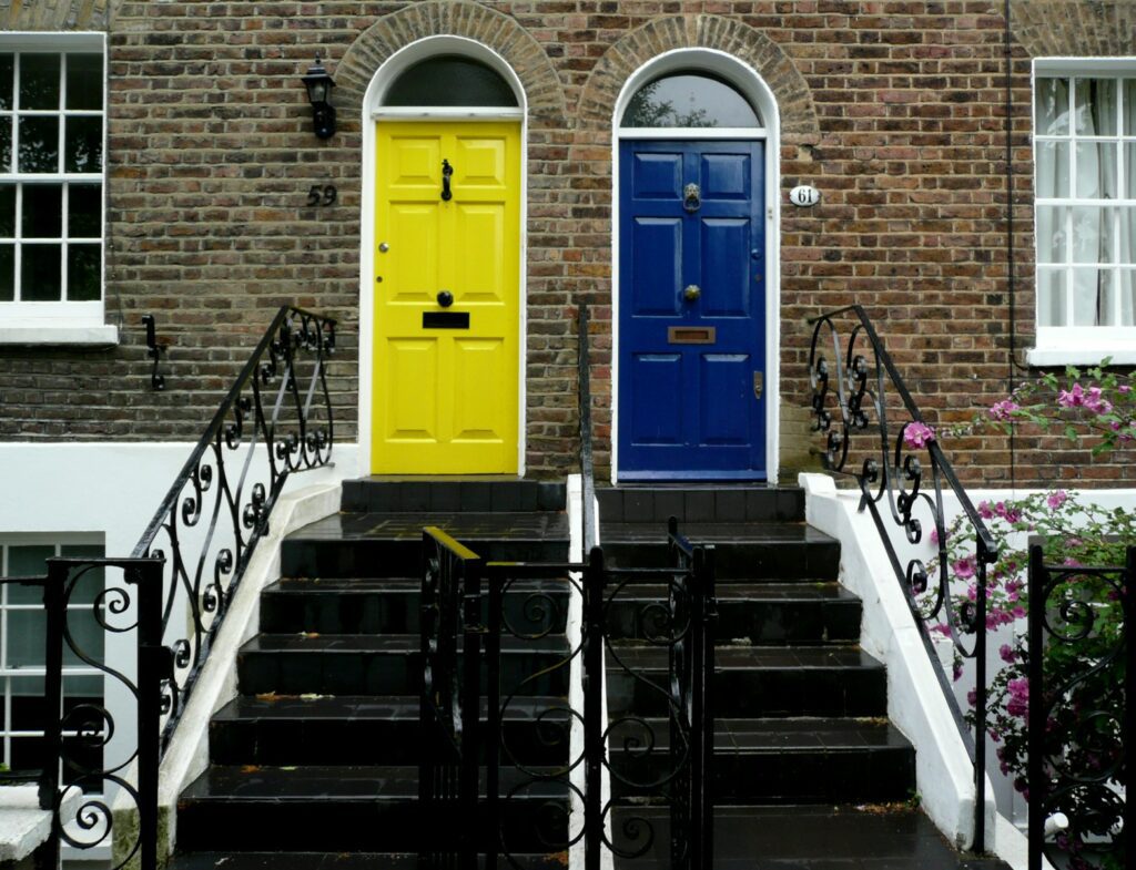 Two colorful doors on brick houses with stairs