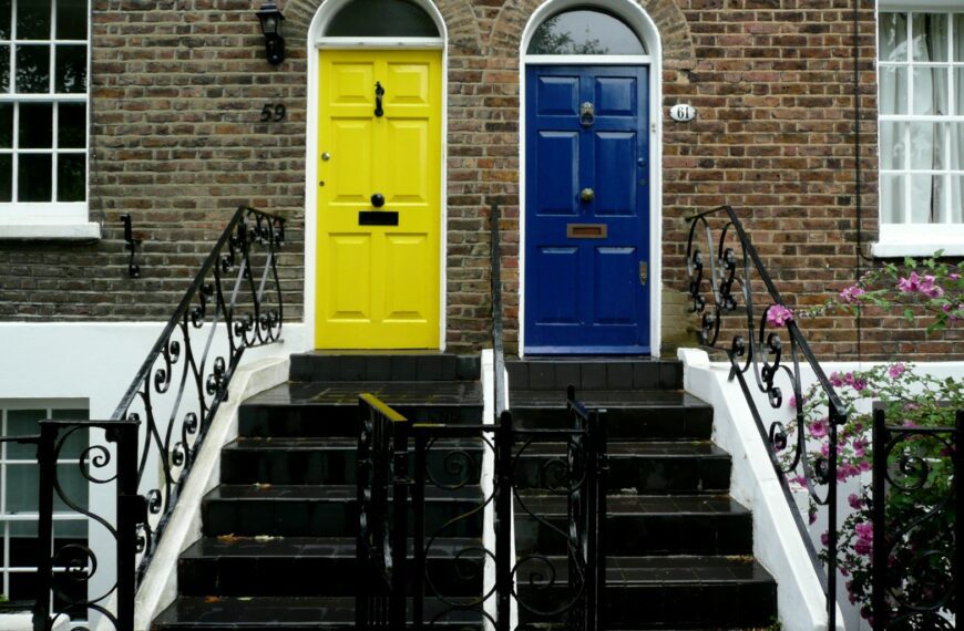 Two colorful doors on brick houses with stairs