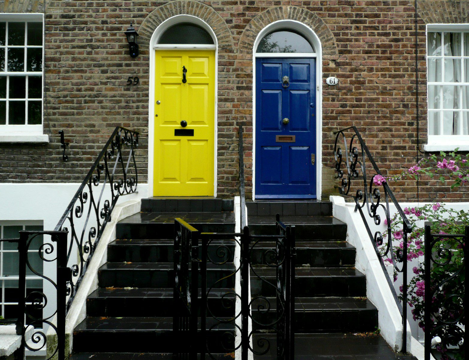 Two colorful doors on brick houses with stairs