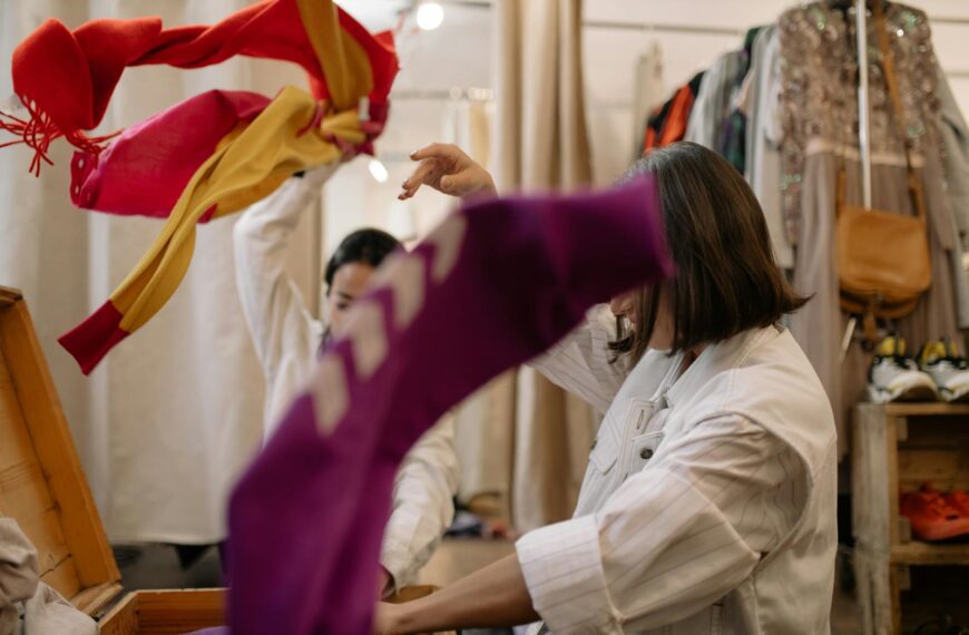 Woman exploring thrift store clothing, showcasing vibrant fashion choices.
