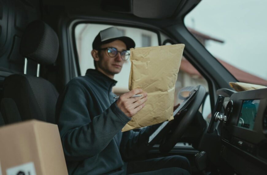Delivery worker examining packages inside a van, focused on logistics.